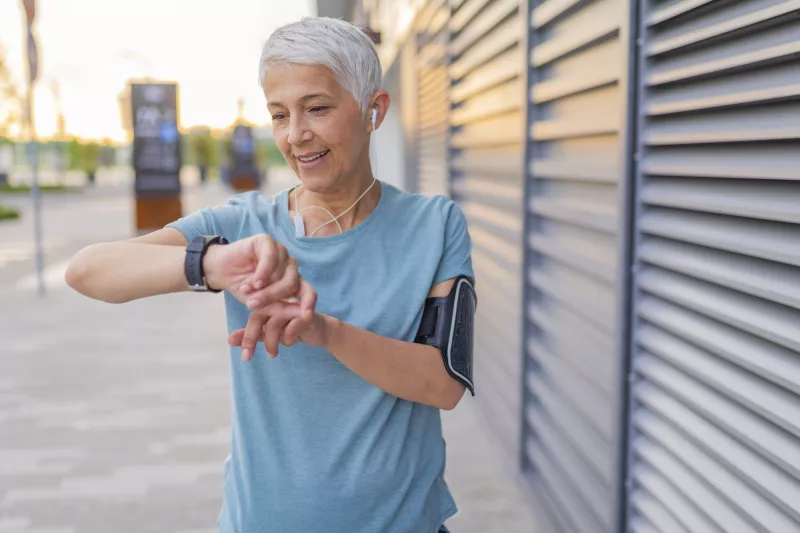 A woman checking her heart rate on a run.