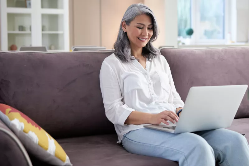 A woman using her computer while sitting on the couch.