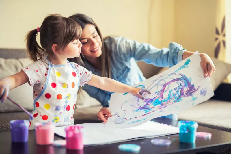 A mother and young daughter painting together.