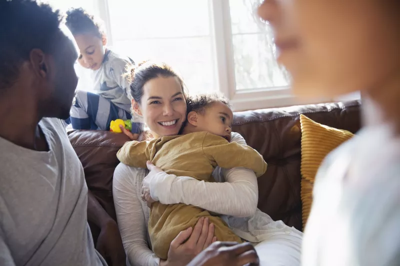 Woman holding child while sitting with family
