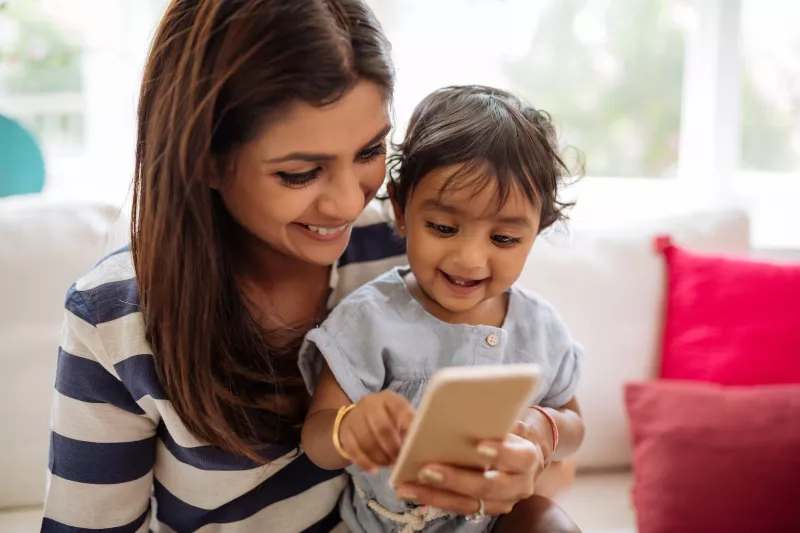 A mom uses her phone with her child.