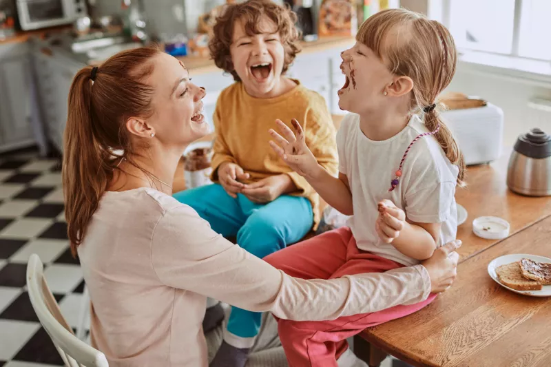 A mom laughs her way through a messy lunch with her kids.