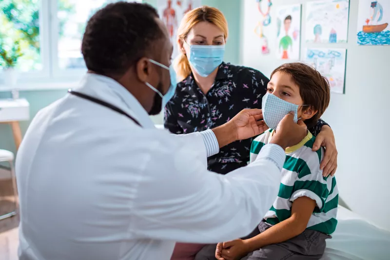 Mother and son at a doctor's office while wearing masks.