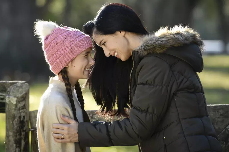 A mother and daughter smiling while outdoors.