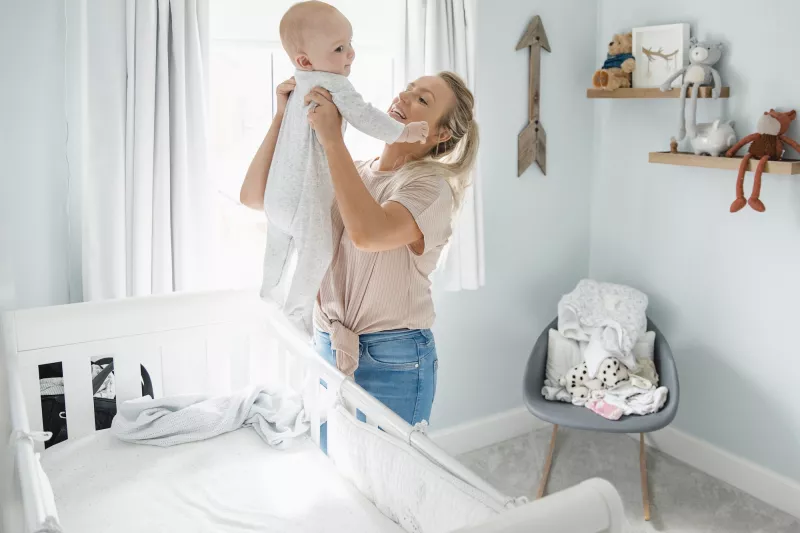 A mom lifts her infant out of the crib.