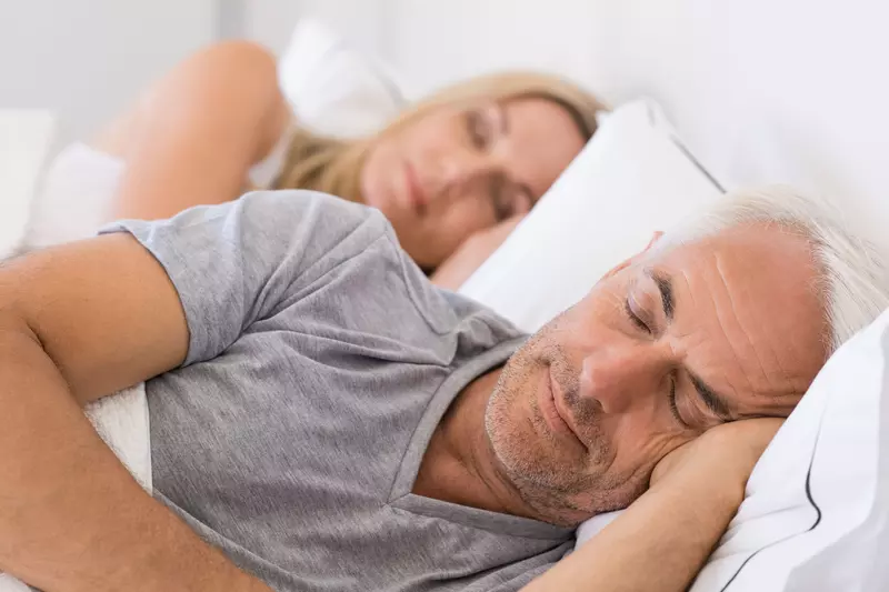 Mature couple sleeping on their bed
