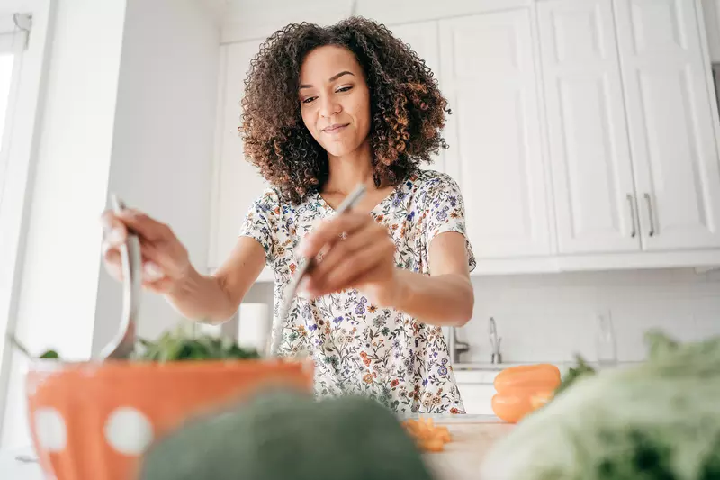 A woman making a salad at home.
