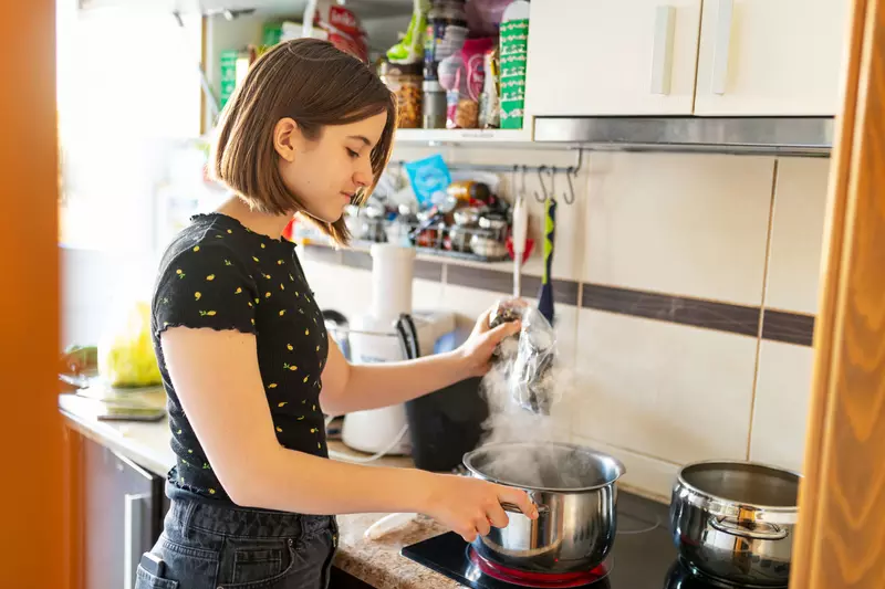 A young lady using her stove in the kitchen