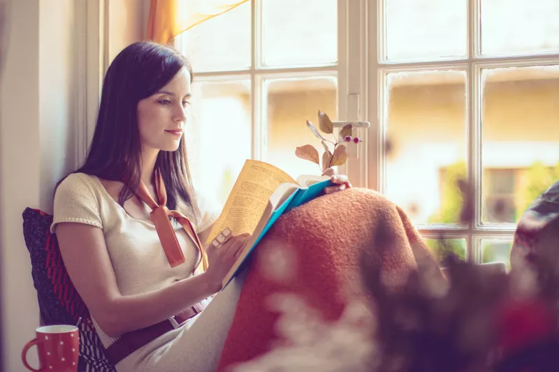 Woman reading near a window.
