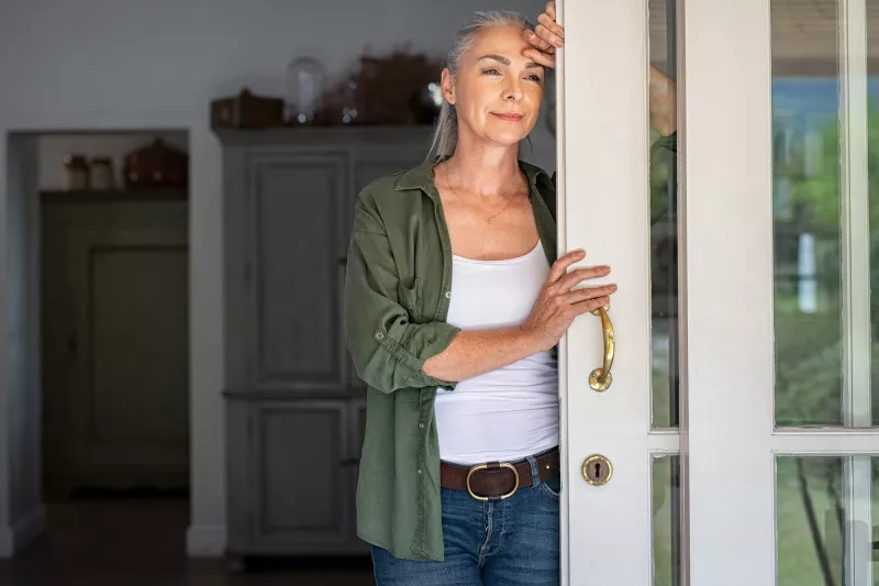 A woman standing by her doorway.