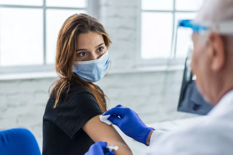 Woman wearing a mask getting her covid-19 vaccine booster shot.