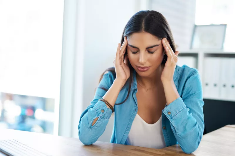 A woman with a headache massaging her temples.