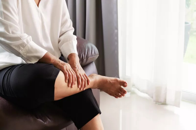 A woman massages her lower legs to relieve the pain