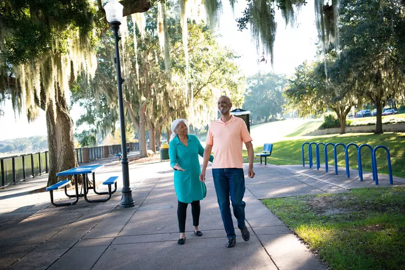 A Couple Walks Through a Park By a Lake in Clermont Florida, Laughing and Enjoying the Outdoors.