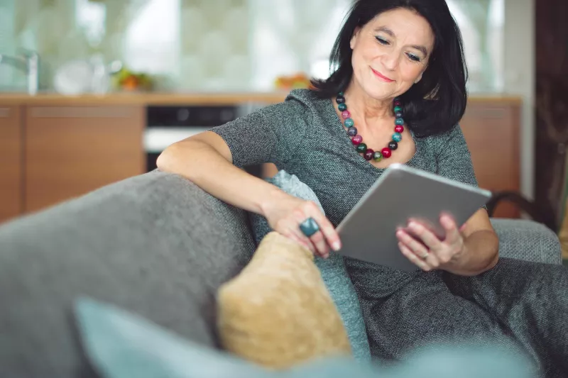 Woman using tablet on couch.