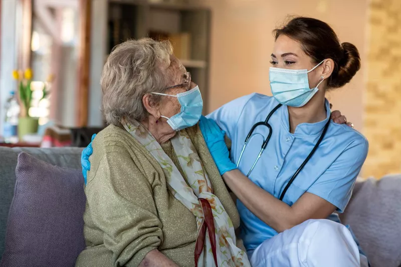 Ederly woman with care specialist wearing face masks