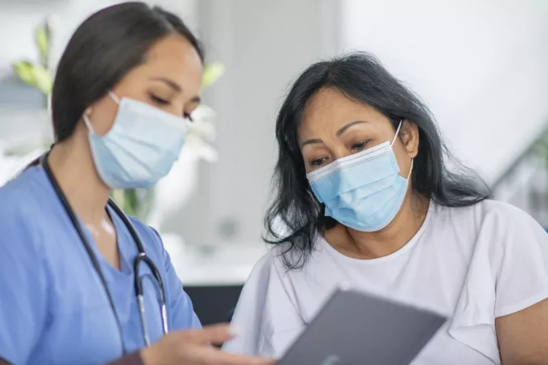 Doctor showing a patient how to schedule an appointment while wearing masks