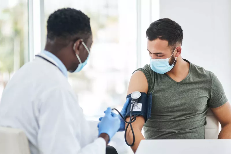 doctor with mask taking blood pressure of patient with mask