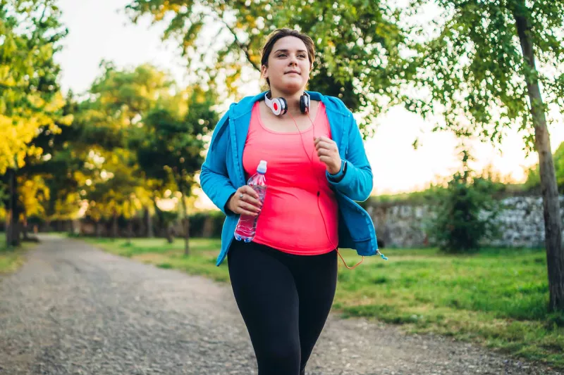 A woman running with headphones and a bottle of water