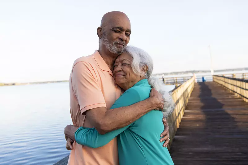 Senior couple hugging while on a dock at a lake.