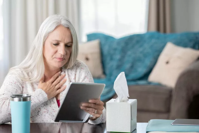 Woman holding heart, looking at tablet