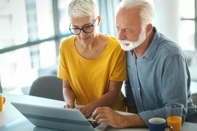 Senior couple viewing a laptop together at the kitchen counter