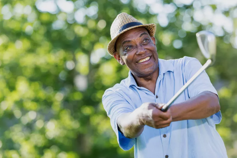 Mature golfer teeing off
