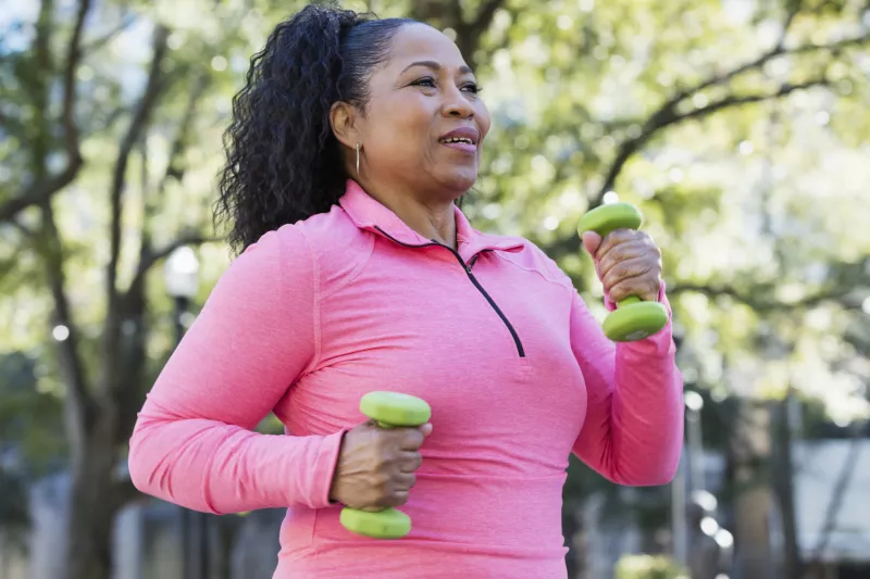 Woman walking outdoors and carrying small hand weights
