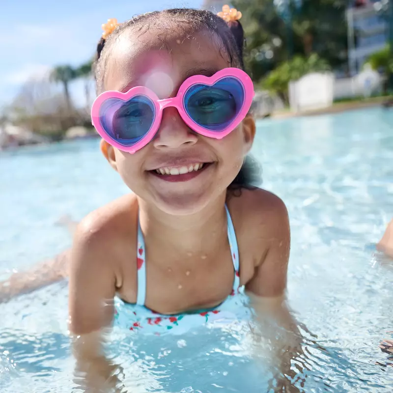A Little Girl Swims in a Resort Pool Wearing Heart Shaped Goggles