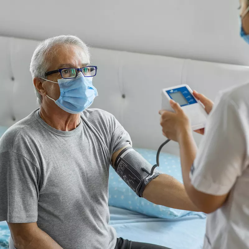 A home care nurse takes a patient's blood pressure.