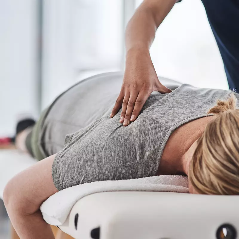 Woman laying face down getting her upper back massages by a therapist