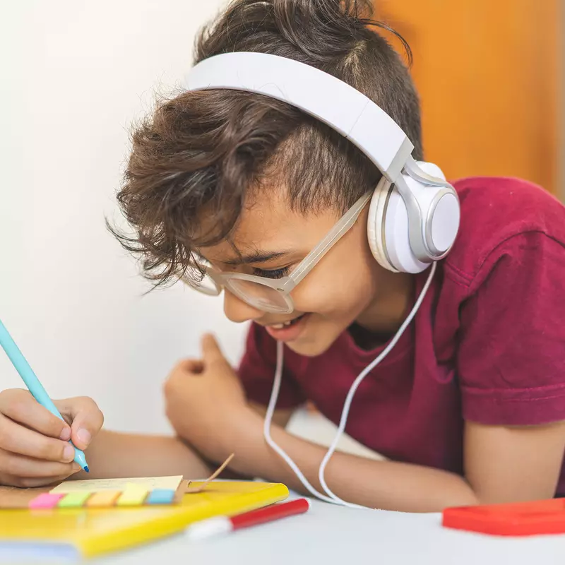 Boy working on schoolwork wearing headphones 