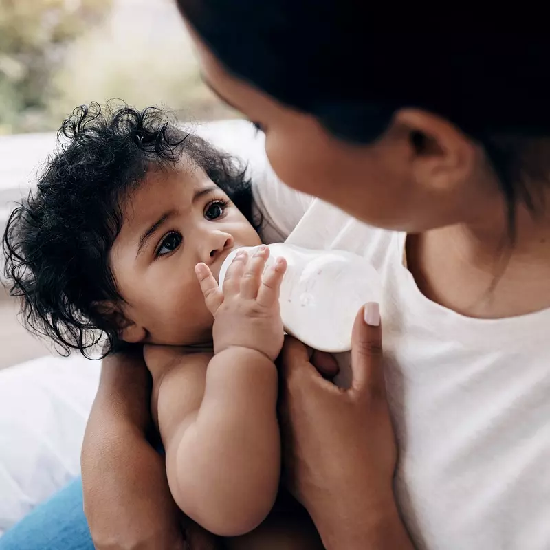 A mother feeding her baby milk in a bottle