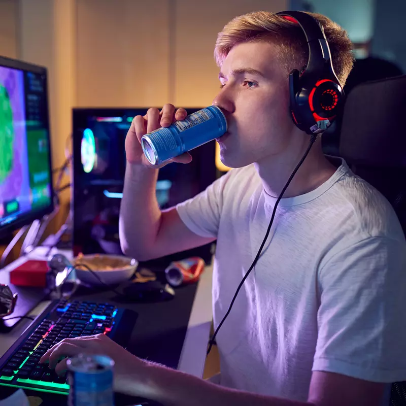 Teenager Drinks an Energy Drink While Playing Video Games with A Headset on.