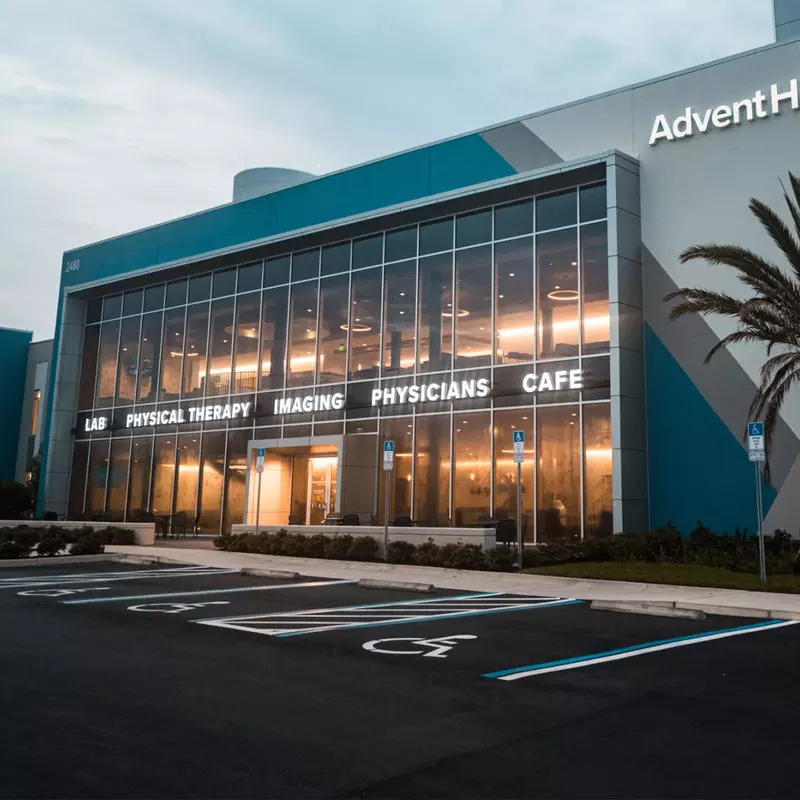 An Exterior Photo of an AdventHealth Health Park Building at Dawn with a Palm Tree in Front.
