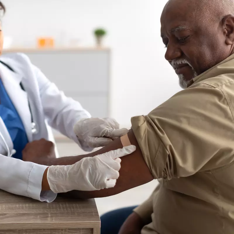 A Physician Puts a Bandage on an Injection Site After a Vaccine