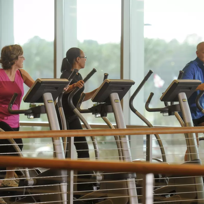 Two women and a man doing cardio.