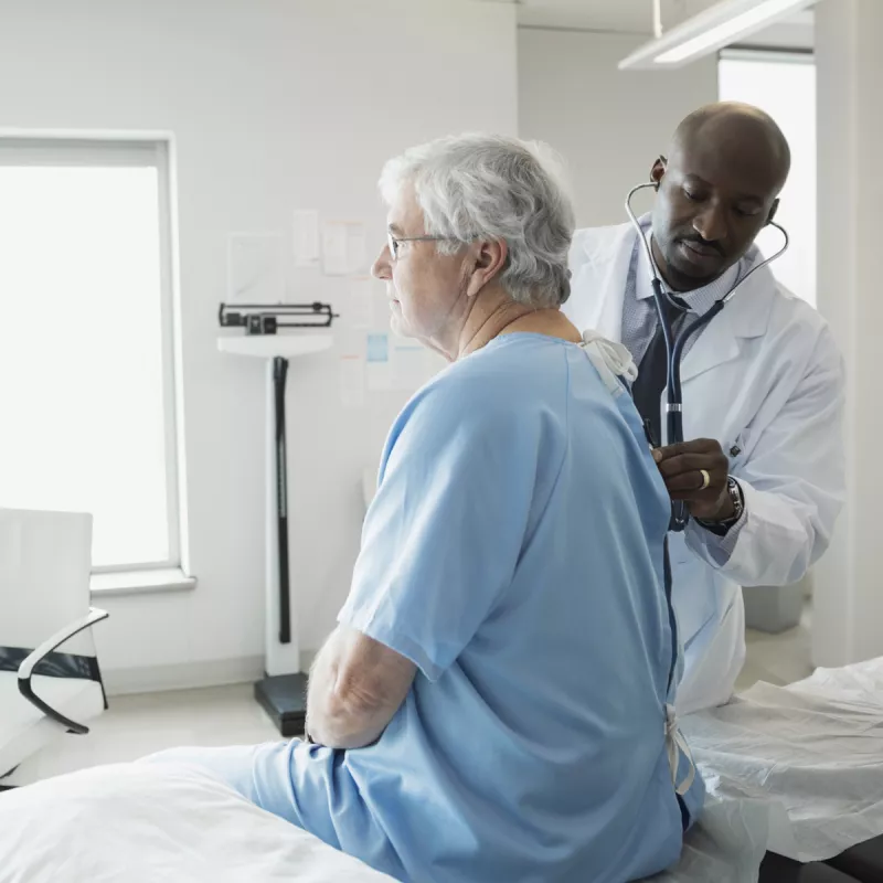 A Caucasian man receives a check-up an African American doctor.