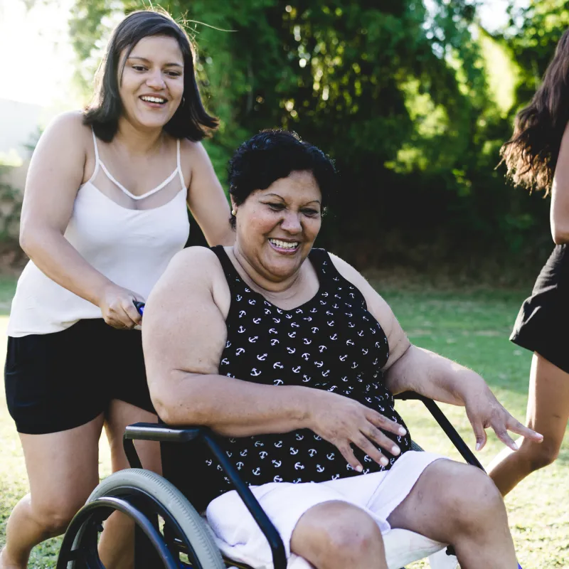 A woman in a wheelchair enjoys the outdoors with her daughters during the summer.