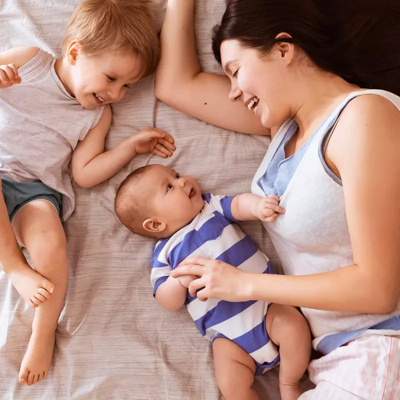 A mom snuggles her two children in bed.