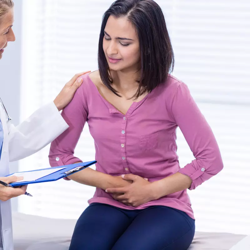 A woman experiencing stomach pain visits her doctor.