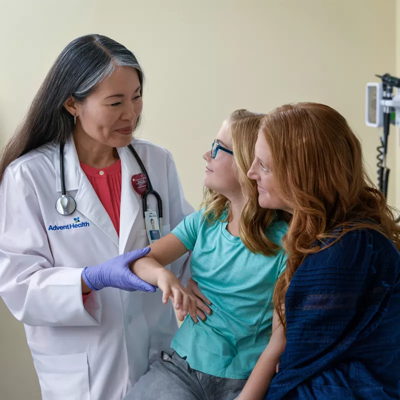 A Centra Care Physician Checks a Little Girl's Arm With Her Mom Watching