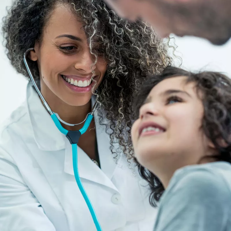 Female doctor checking a young child's heartbeat