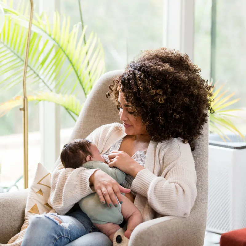 A mother on her couch and breastfeeding her child