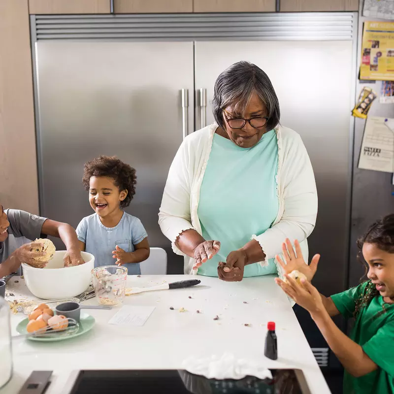 A grandmother baking with her three grand-kids in the kitchen.