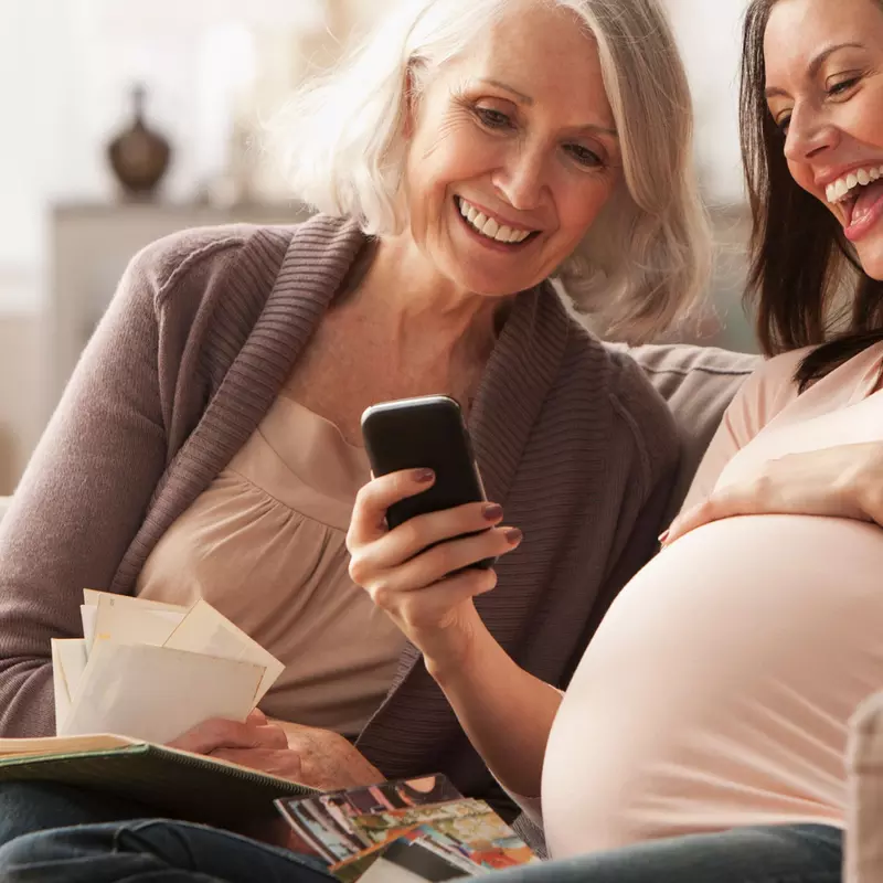 A pregnant woman with her mom looking something on her cell phone