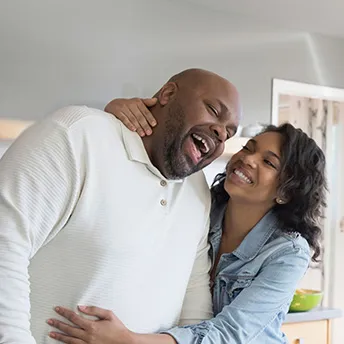 A couple hugging each other while cooking on the kitchen