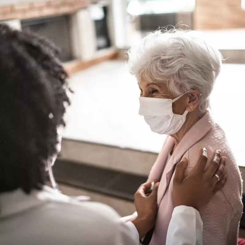 An elderly woman being comforted by her doctor