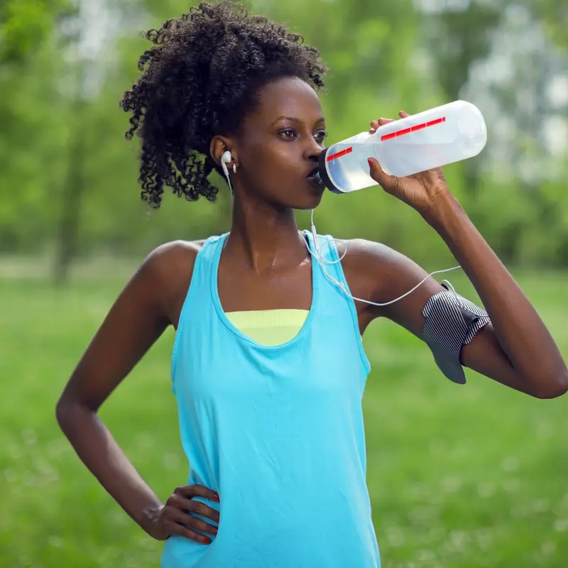 A woman taking a water break during her run.