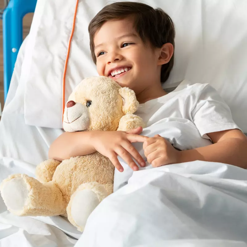 A little boy hugs his teddy bear while in the hospital.